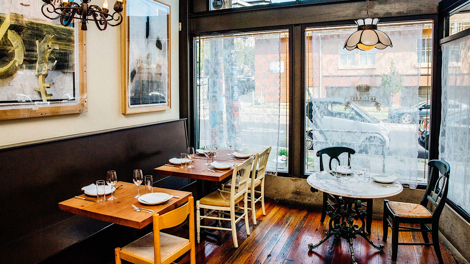 The Cascina Spinasse dining room with large windows, wooden chairs and tables and a lighting fixture that looks like a flower